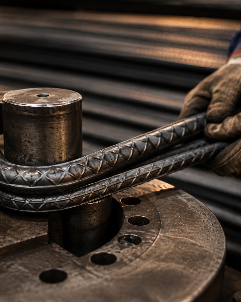 Worker performing a bend test on Omega reinforcement bars